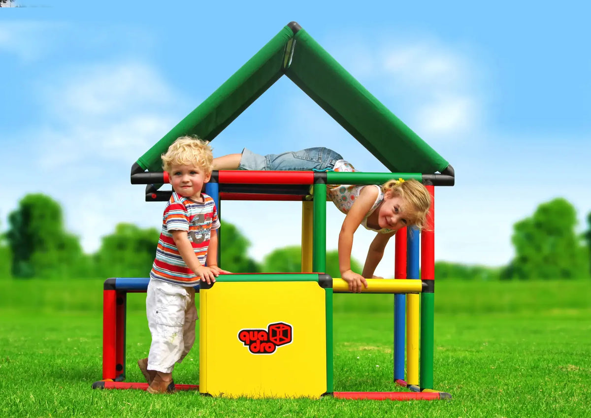 Three children climbing on an open QUADRO Junior playhouse outdoors