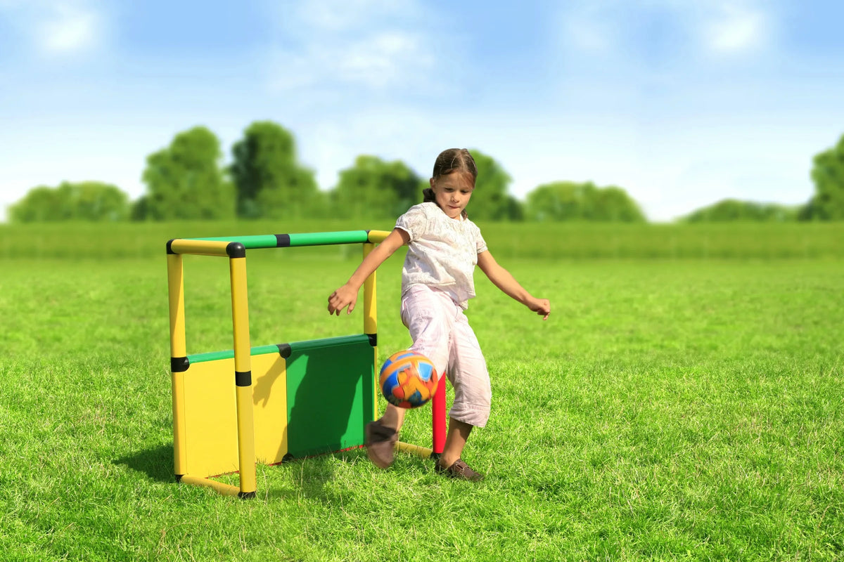 Child kicking a ball beside a low QUADRO Starter goal and storage panel